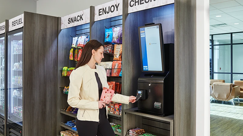 A person paying for a snack at a micro market self-checkout kiosk with a contactless card tap